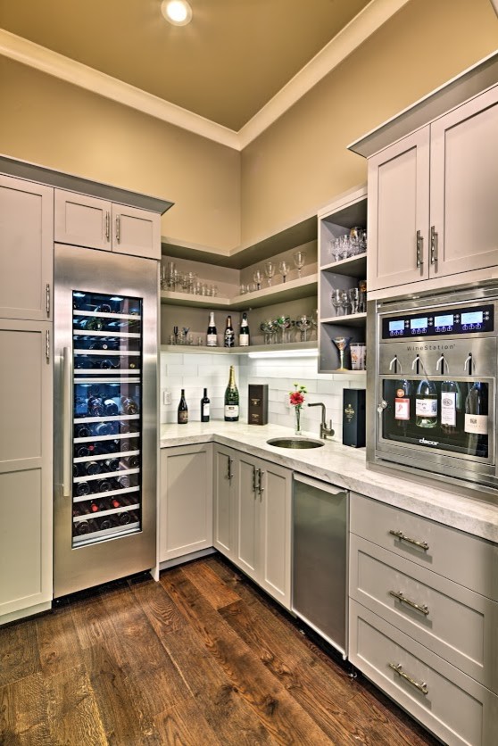 Foto de bar en casa con fregadero en L tradicional renovado pequeño con fregadero bajoencimera, armarios estilo shaker, puertas de armario beige, encimera de piedra caliza, salpicadero blanco, salpicadero de azulejos de vidrio, suelo de madera oscura y suelo marrón