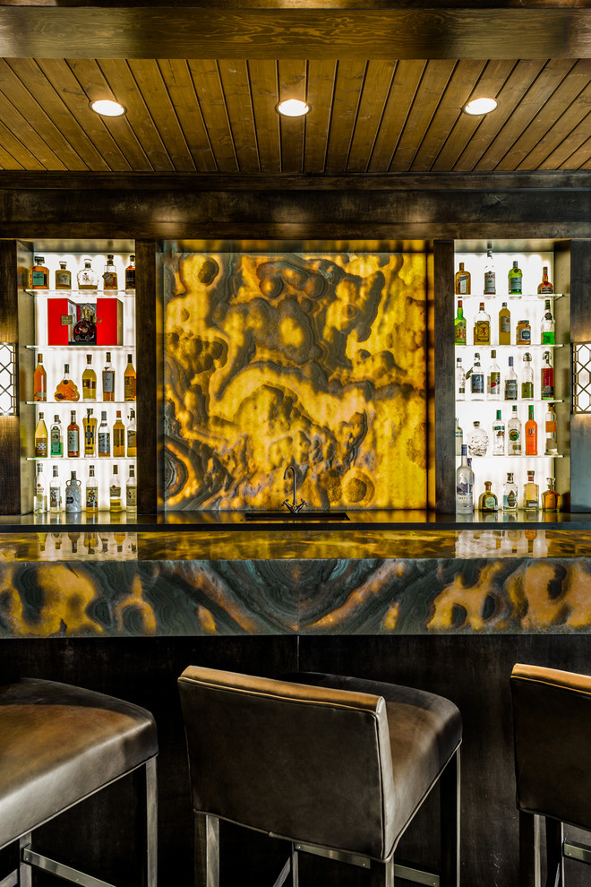 Esempio di un ampio bancone bar contemporaneo con lavello sottopiano, nessun'anta, ante in legno bruno, top in onice, paraspruzzi giallo, paraspruzzi in lastra di pietra e parquet scuro