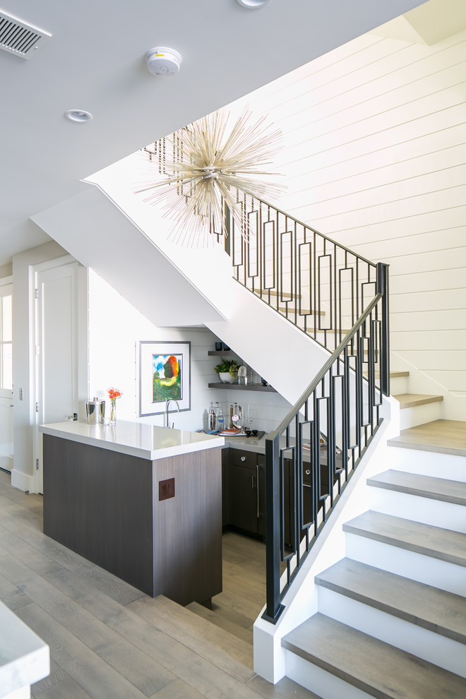 Elegant wooden spiral metal railing staircase photo in Orange County with painted risers