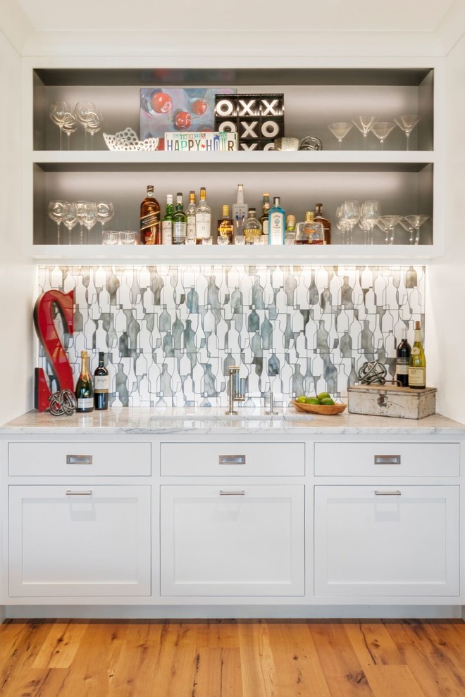 Traditional single-wall wet bar in Cleveland with a submerged sink, shaker cabinets, white cabinets, grey splashback, medium hardwood flooring, brown floors and white worktops.