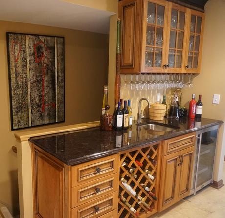 Medium sized traditional single-wall wet bar in Philadelphia with a submerged sink, raised-panel cabinets, medium wood cabinets, granite worktops, porcelain flooring and beige floors.