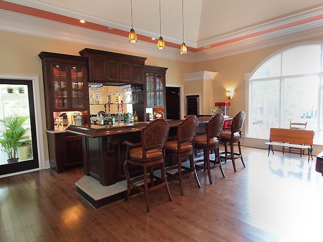 Esempio di un bancone bar classico di medie dimensioni con lavello sottopiano, ante di vetro, ante in legno bruno, top in legno, paraspruzzi a specchio, parquet scuro e top marrone