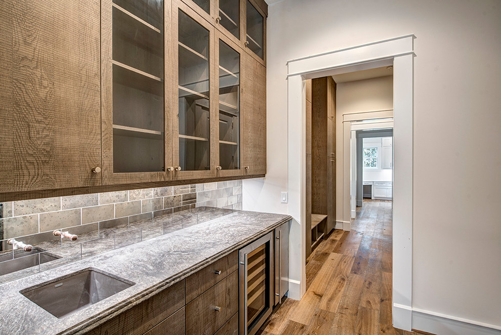 Klassische Hausbar mit Marmor-Arbeitsplatte, Rückwand aus Spiegelfliesen und hellem Holzboden in Houston
