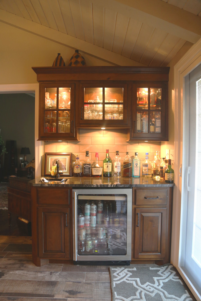 Foto på en liten vintage linjär hemmabar med vask, med en undermonterad diskho, luckor med upphöjd panel, skåp i mellenmörkt trä, granitbänkskiva, beige stänkskydd, stänkskydd i porslinskakel och klinkergolv i porslin