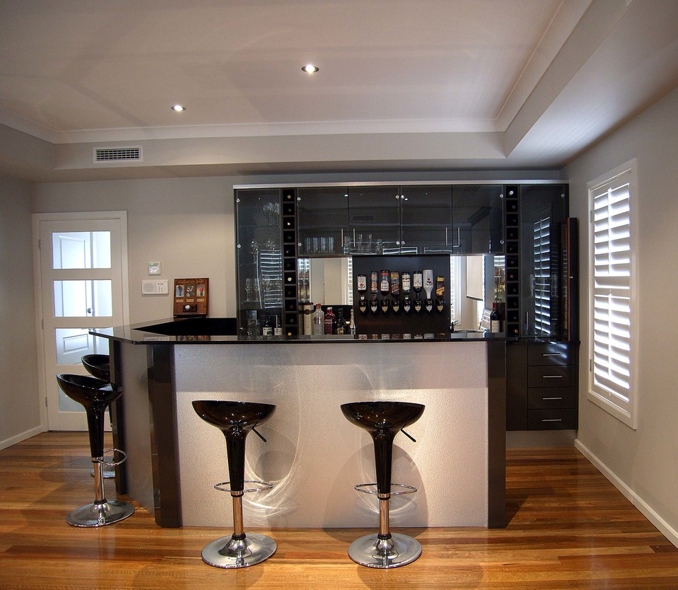 Diseño de bar en casa con barra de bar en U moderno de tamaño medio con armarios con paneles lisos, puertas de armario negras, encimera de granito y salpicadero negro