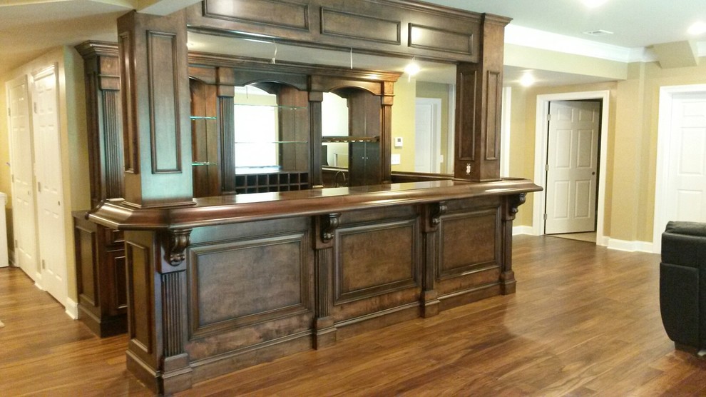 Foto de bar en casa con barra de bar de galera tradicional grande con puertas de armario de madera en tonos medios, encimera de madera y suelo de madera en tonos medios