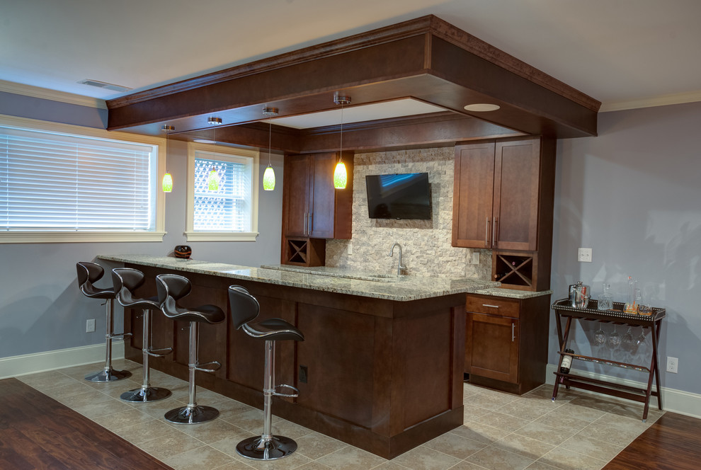 Foto de bar en casa con barra de bar de galera actual de tamaño medio con armarios estilo shaker, puertas de armario de madera en tonos medios, encimera de granito, salpicadero beige, salpicadero de azulejos de piedra y suelo de baldosas de cerámica