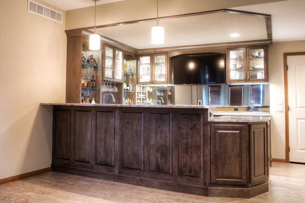 Photo of a large classic u-shaped wet bar in Other with raised-panel cabinets, dark wood cabinets, engineered stone countertops, mirror splashback, vinyl flooring and grey floors.