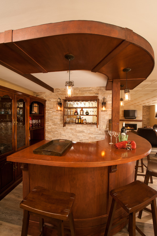 Aménagement d'un grand bar de salon parallèle craftsman en bois foncé avec des tabourets, un placard sans porte, un plan de travail en bois, une crédence beige, une crédence en carrelage de pierre et un sol en bois brun.