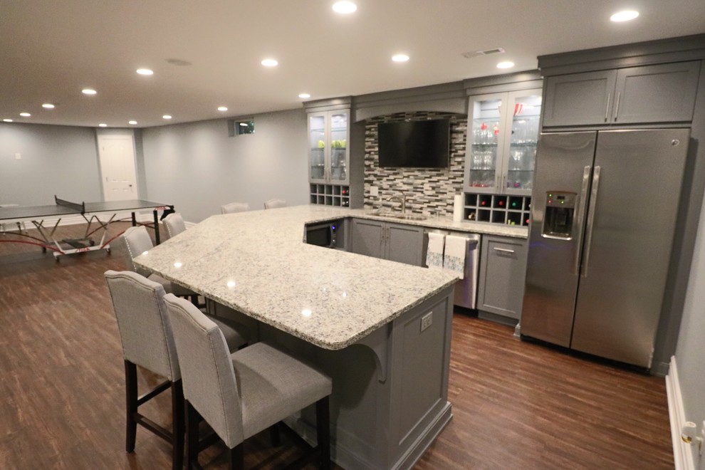 Photo of an expansive contemporary u-shaped breakfast bar in Louisville with a submerged sink, glass-front cabinets, grey cabinets, granite worktops, multi-coloured splashback, matchstick tiled splashback, medium hardwood flooring, brown floors and grey worktops.