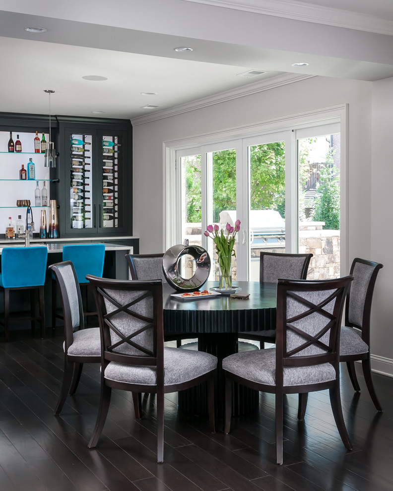 Modern inredning av en mycket stor blå parallell blått hemmabar med stolar, med en undermonterad diskho, släta luckor, svarta skåp, bänkskiva i kvarts, mörkt trägolv, brunt golv och glaspanel som stänkskydd