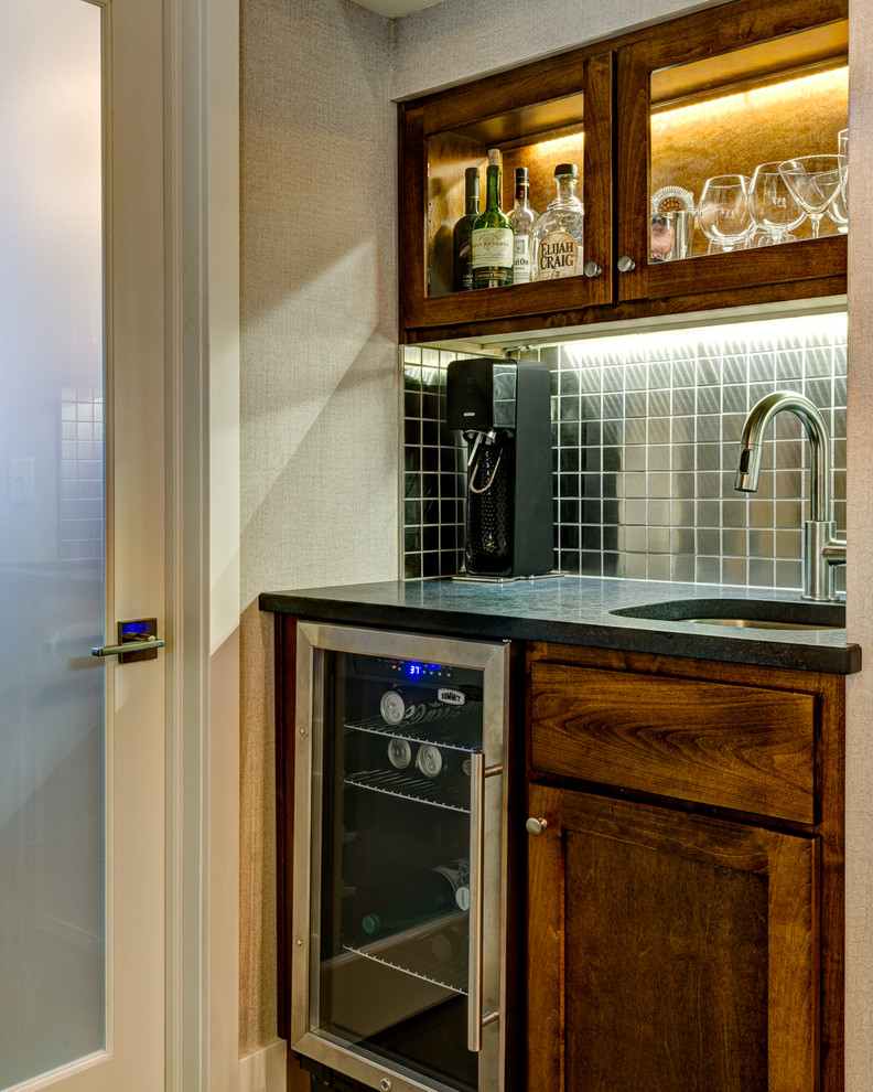 Example of a mid-sized trendy single-wall concrete floor wet bar design in Los Angeles with an undermount sink, brown cabinets, soapstone countertops, gray backsplash, metal backsplash and shaker cabinets