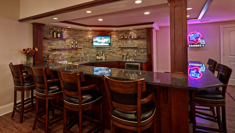 Seated home bar - huge traditional u-shaped seated home bar idea in Philadelphia with raised-panel cabinets, brown cabinets, granite countertops and multicolored backsplash