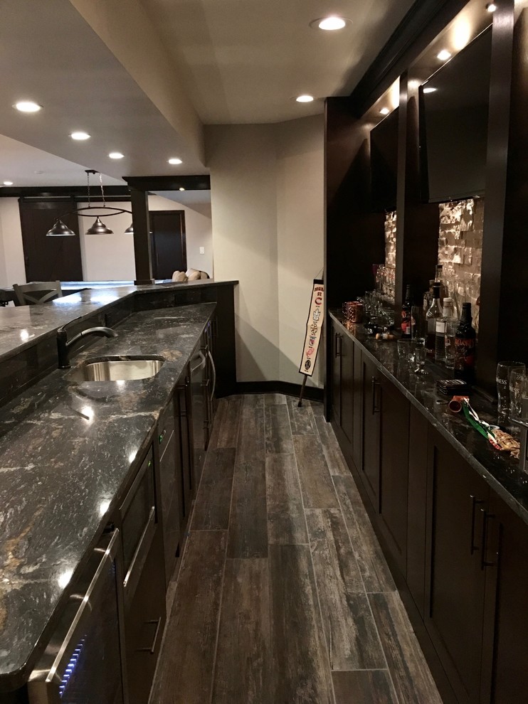 Design ideas for a large classic galley breakfast bar in Chicago with a submerged sink, shaker cabinets, dark wood cabinets, granite worktops, beige splashback, stone tiled splashback, porcelain flooring and brown floors.
