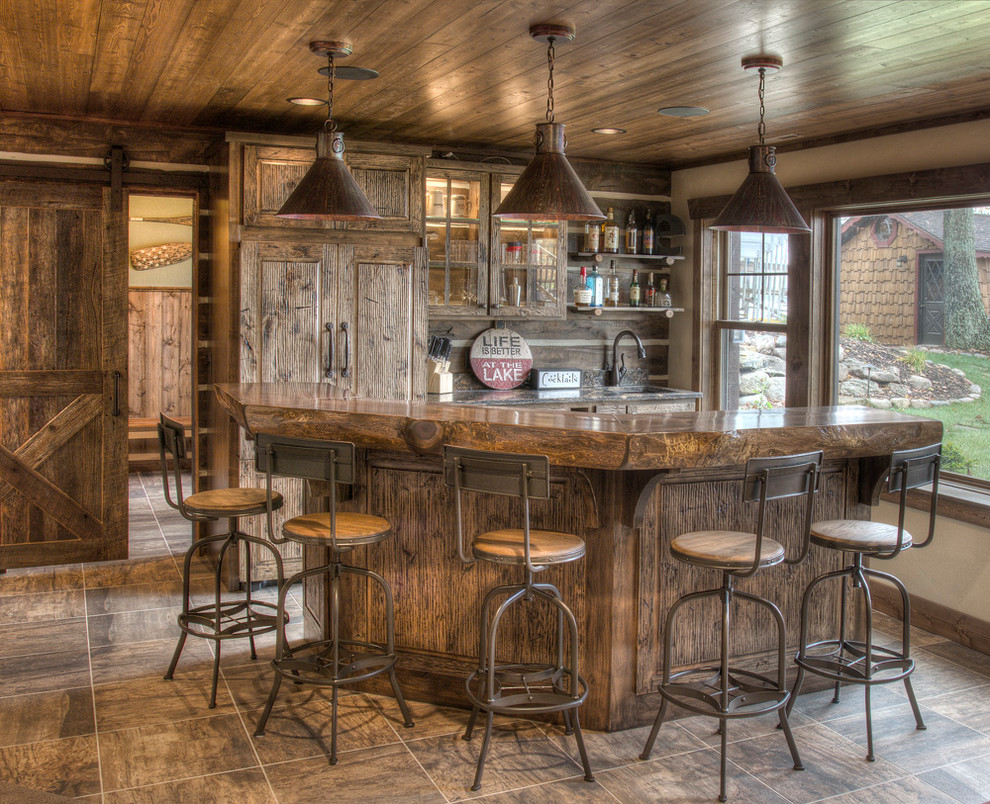 Idée de décoration pour un bar de salon chalet en bois foncé avec un plan de travail en bois, un sol en carrelage de céramique, des tabourets, un placard avec porte à panneau surélevé et un plan de travail marron.