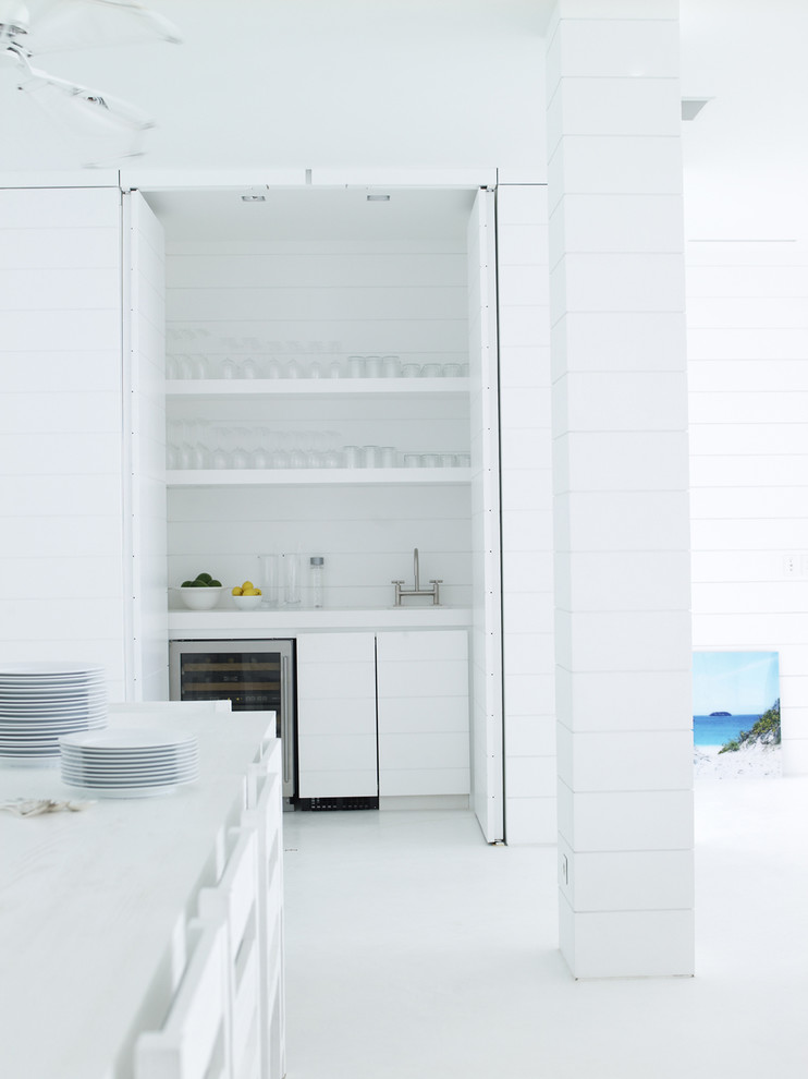 Design ideas for a small world-inspired single-wall wet bar in Other with concrete flooring, flat-panel cabinets, white cabinets, white splashback, white floors, a built-in sink and wood splashback.
