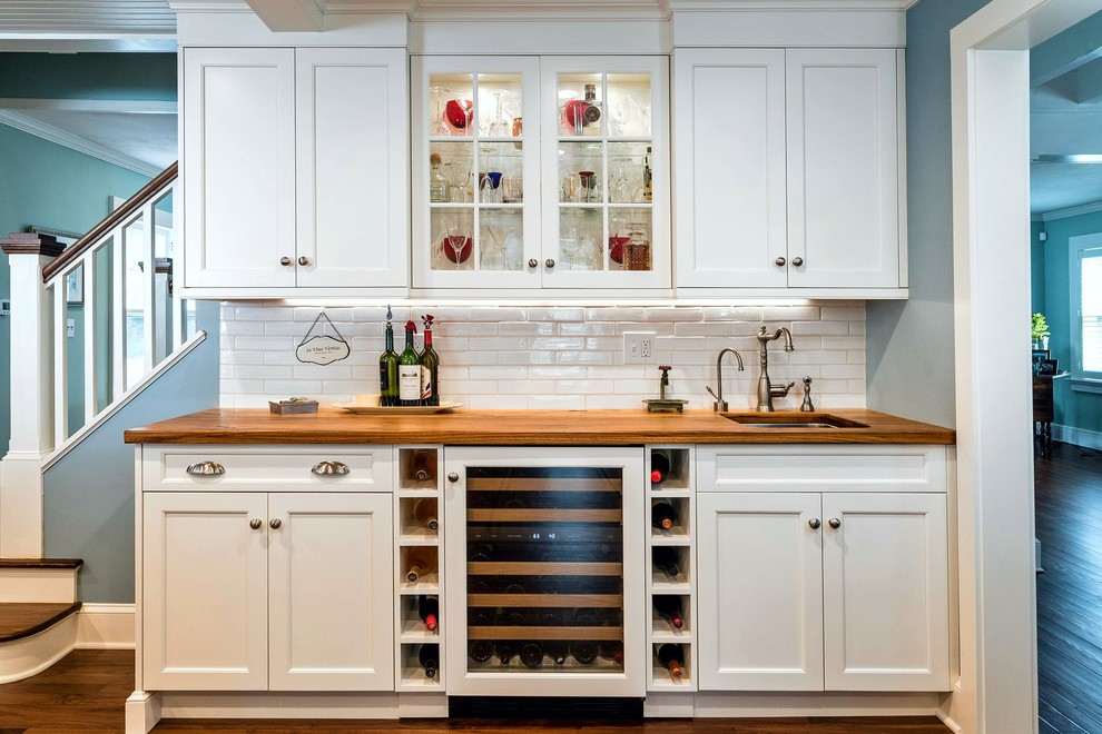 Large nautical single-wall wet bar in Bridgeport with white cabinets, wood worktops, white splashback, ceramic splashback, a submerged sink, glass-front cabinets and brown worktops.