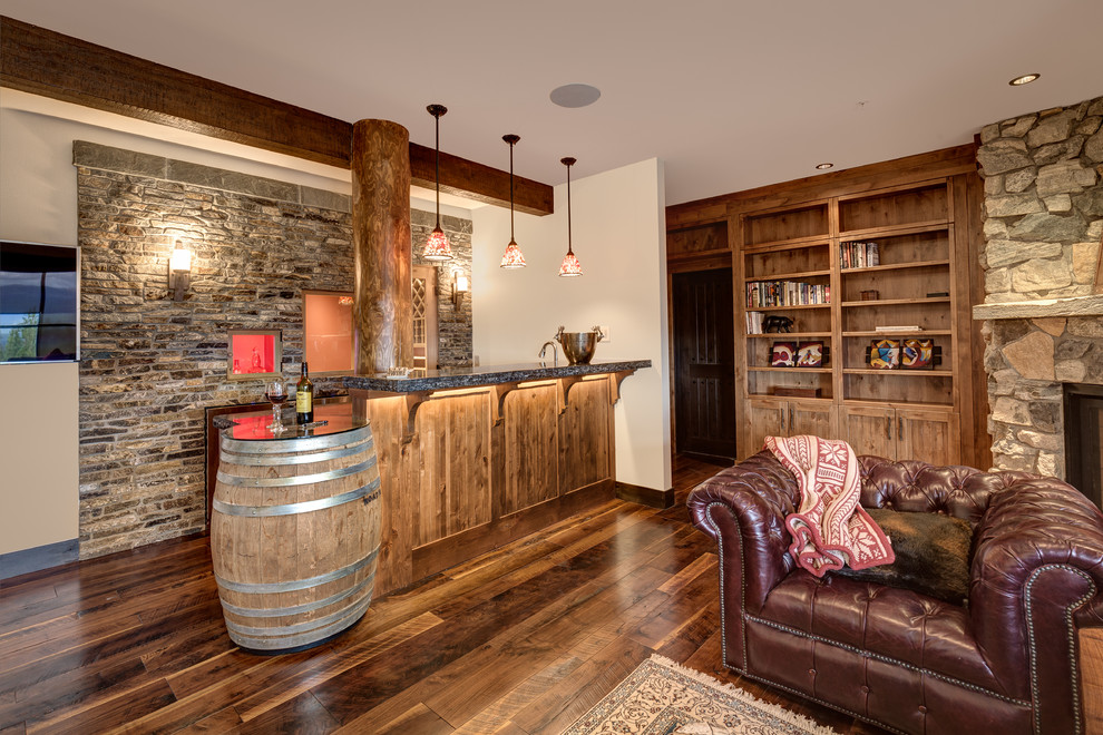 Exemple d'un bar de salon montagne en bois brun avec un évier encastré, un placard à porte affleurante, un plan de travail en surface solide, une crédence multicolore, une crédence en carrelage de pierre et un sol en bois brun.