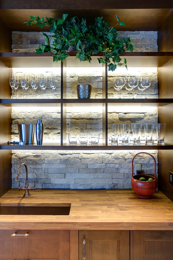 Esempio di un angolo bar con lavandino rustico con lavello sottopiano, ante con riquadro incassato, ante marroni, top in legno, top marrone e paraspruzzi grigio