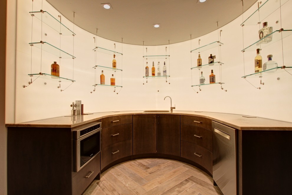 Foto på en stor funkis u-formad hemmabar med vask, med en undermonterad diskho, släta luckor, skåp i mörkt trä, vitt stänkskydd och ljust trägolv