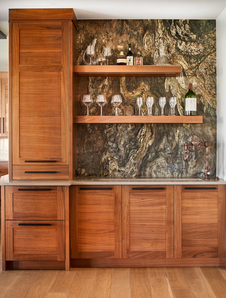 Cette photo montre un bar de salon avec évier méditerranéen en bois brun de taille moyenne avec un évier encastré, un placard à porte shaker, une crédence multicolore, une crédence en dalle de pierre, un sol en bois brun et un sol marron.