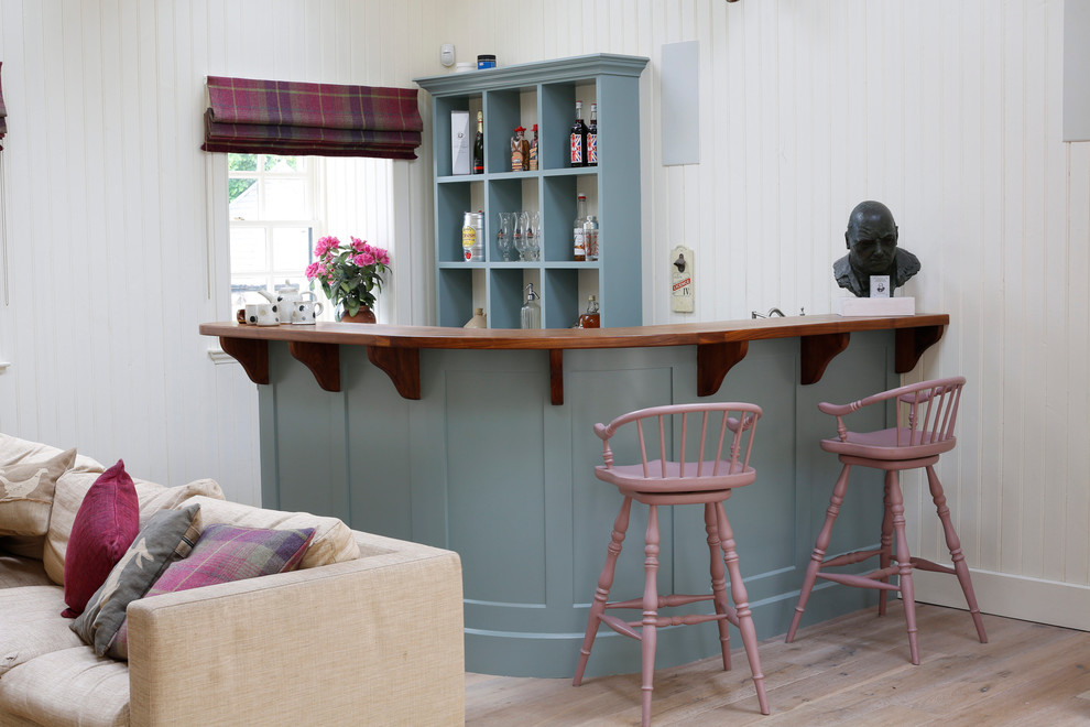 Modelo de bar en casa con barra de bar clásico con puertas de armario azules, encimera de madera y encimeras marrones