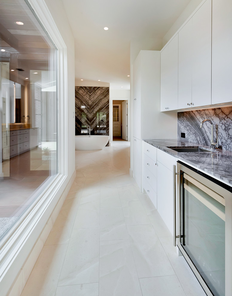 Photo of a medium sized contemporary single-wall wet bar in Dallas with a submerged sink, flat-panel cabinets, white cabinets and stone slab splashback.