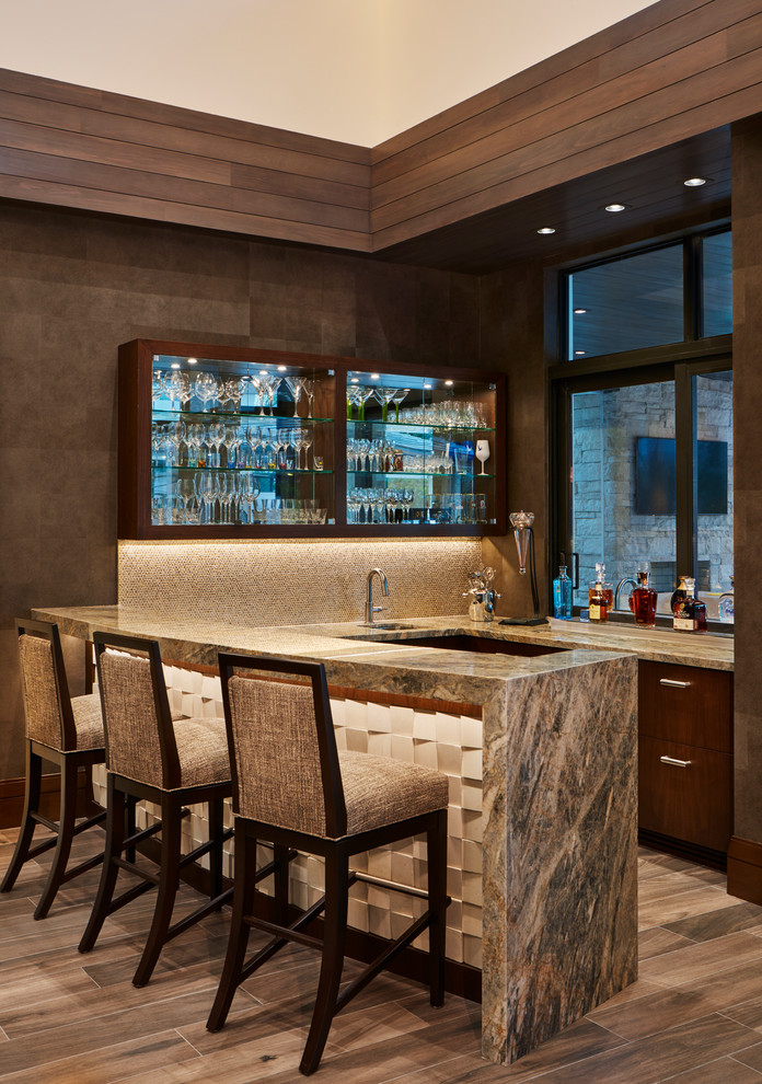 Idee per un bancone bar contemporaneo con lavello sottopiano, ante lisce, ante in legno bruno, top in marmo, paraspruzzi beige e parquet scuro