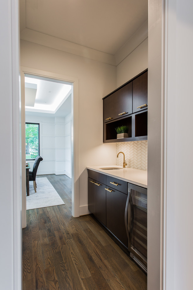 Small minimalist single-wall medium tone wood floor and brown floor wet bar photo in Charlotte with an undermount sink, flat-panel cabinets, brown cabinets, quartz countertops and beige backsplash