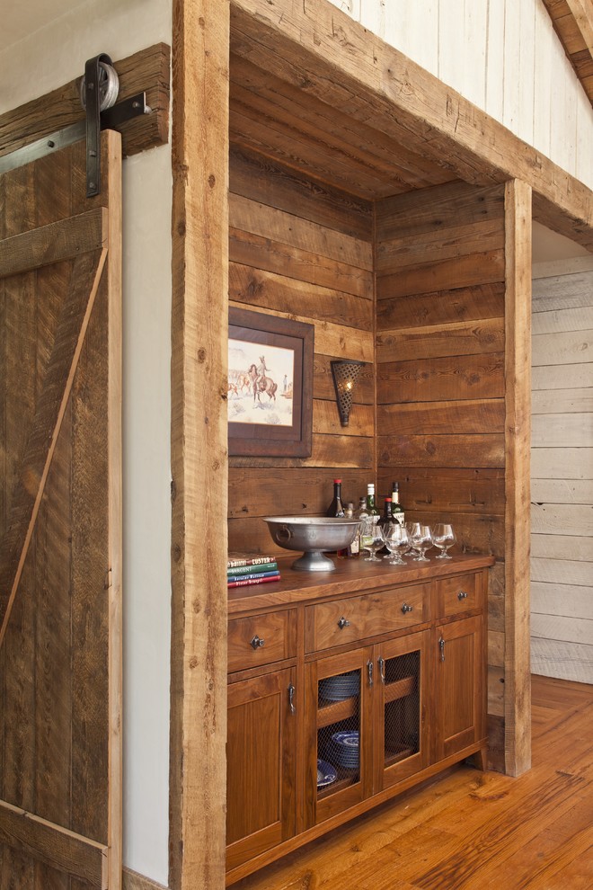 Foto di un piccolo angolo bar rustico con nessun lavello, ante in legno scuro, top in legno e pavimento in legno massello medio