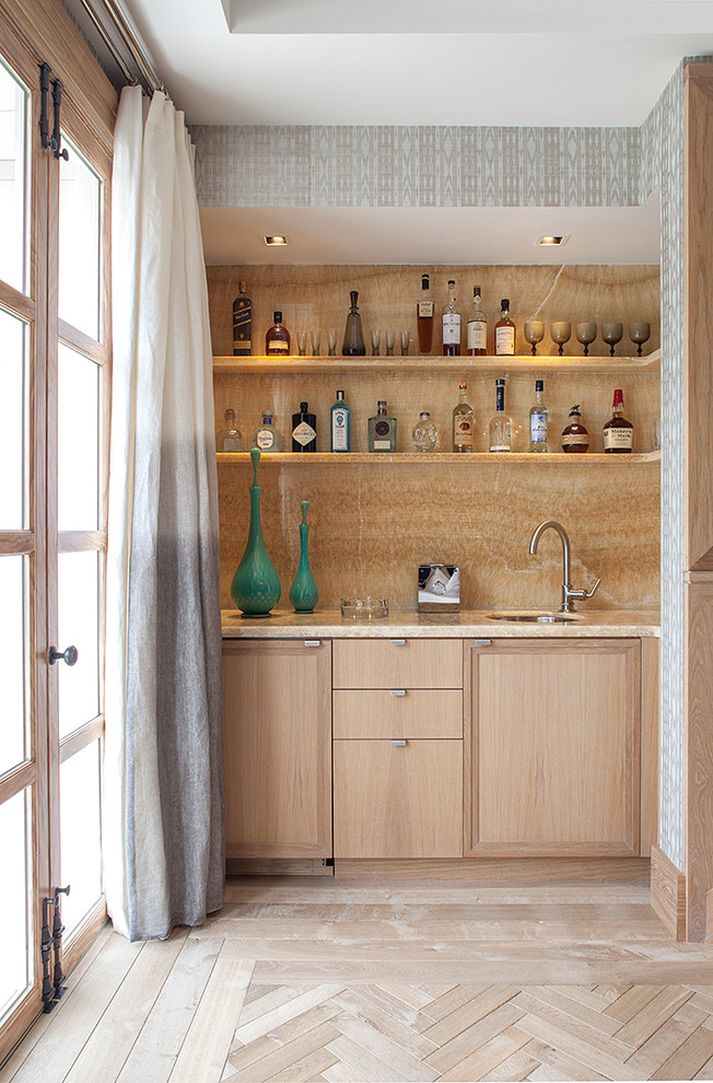 Cette photo montre un bar de salon avec évier linéaire tendance en bois clair avec parquet clair, un évier encastré, un placard à porte plane, une crédence beige et un sol beige.