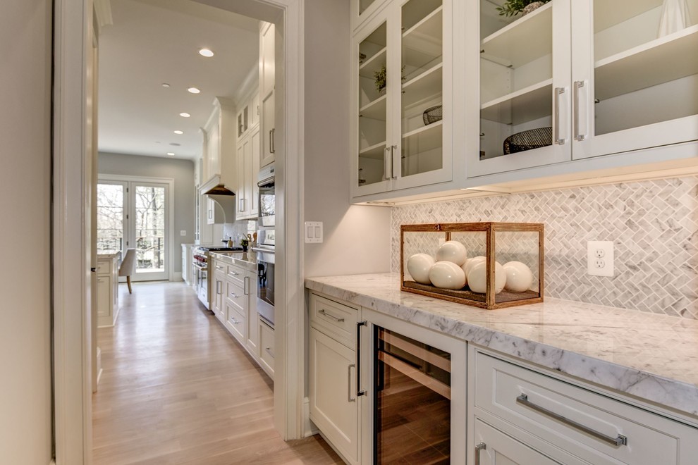 Example of a mid-sized transitional single-wall light wood floor and brown floor wet bar design in DC Metro with recessed-panel cabinets, white cabinets, marble countertops, multicolored backsplash, marble backsplash, multicolored countertops and no sink