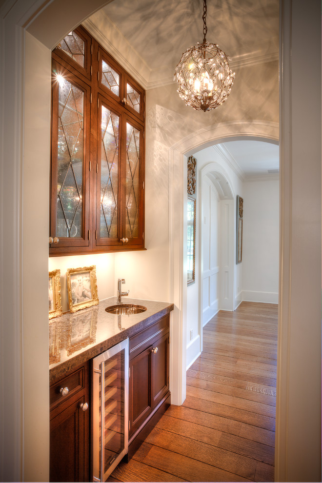 Small transitional galley medium tone wood floor wet bar photo in Indianapolis with an undermount sink, flat-panel cabinets, dark wood cabinets, granite countertops and brown countertops