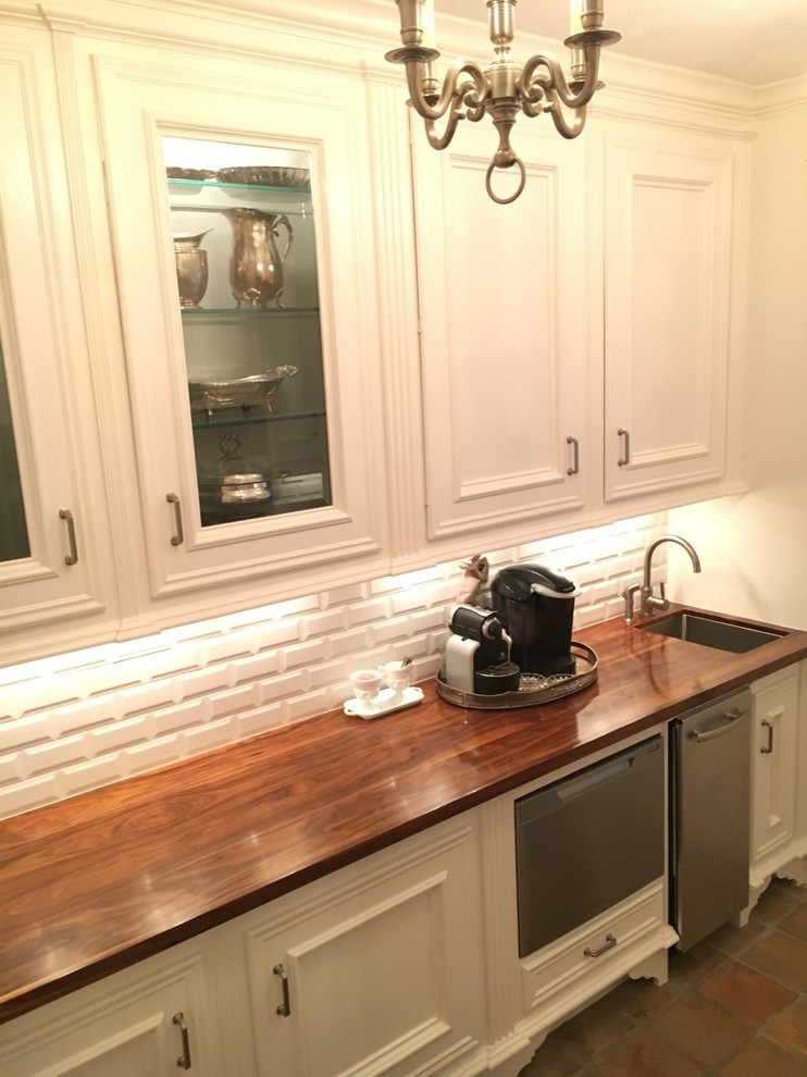 Klassische Hausbar mit weißen Schränken, Arbeitsplatte aus Holz, Küchenrückwand in Weiß und Rückwand aus Metrofliesen in Houston