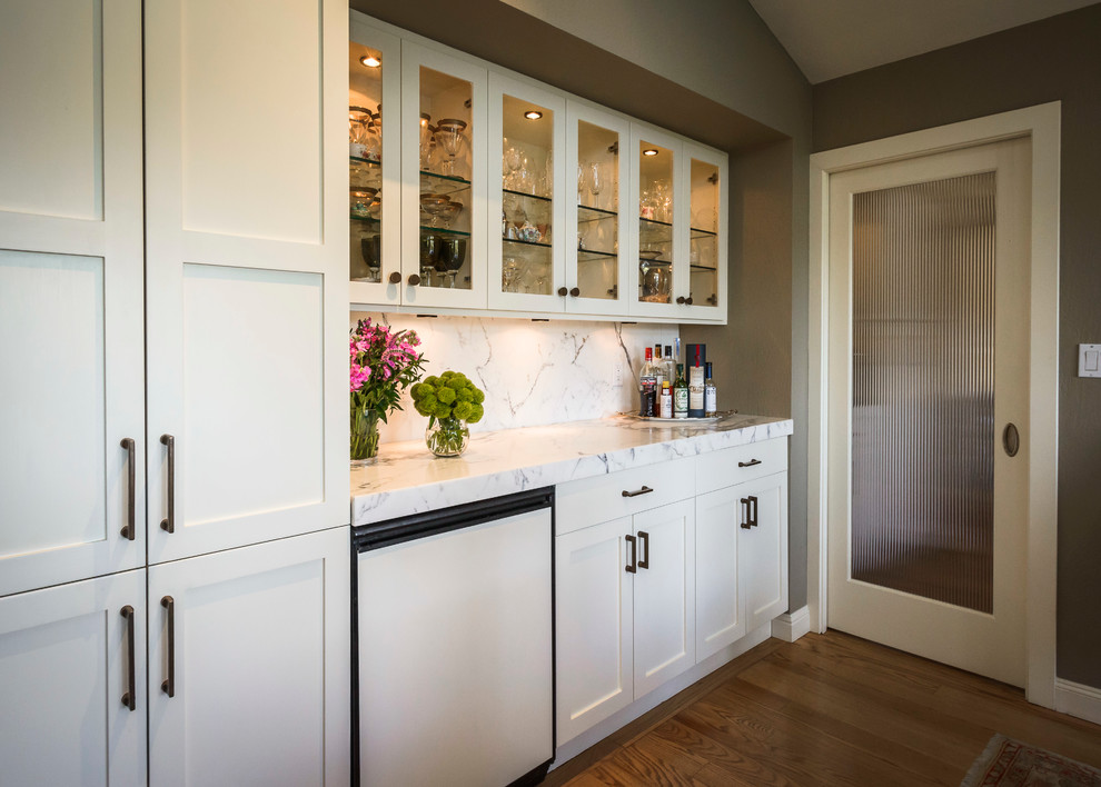Inspiration for a mid-sized farmhouse single-wall medium tone wood floor wet bar remodel in San Francisco with no sink, shaker cabinets, white cabinets, marble countertops and stone slab backsplash