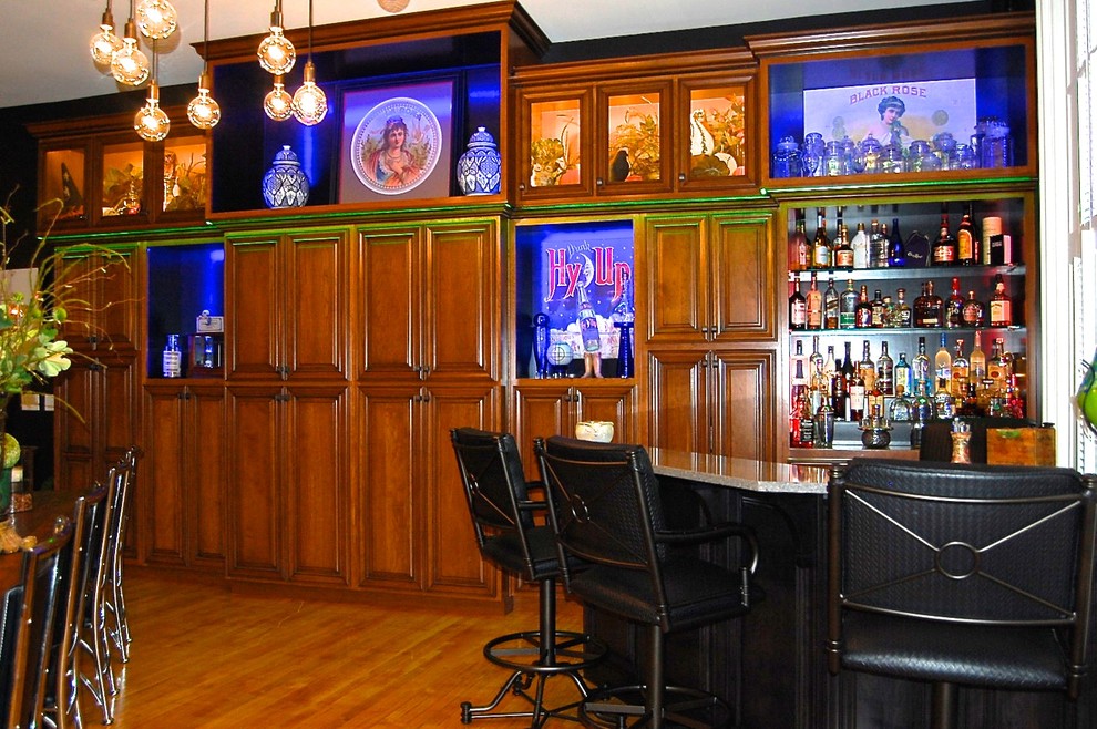 Exemple d'un grand bar de salon chic en U et bois brun avec des tabourets, un évier encastré, un placard à porte vitrée, une crédence multicolore, un sol en bois brun et un sol marron.