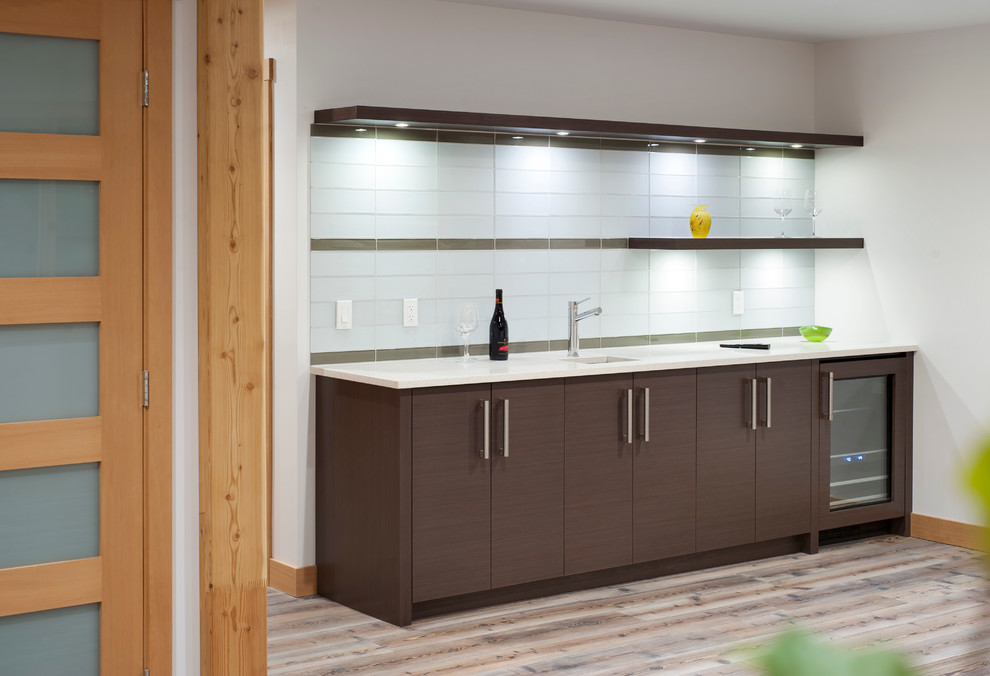 Photo of a contemporary single-wall home bar in Calgary with a submerged sink, flat-panel cabinets, white cabinets, quartz worktops, mosaic tiled splashback and dark hardwood flooring.