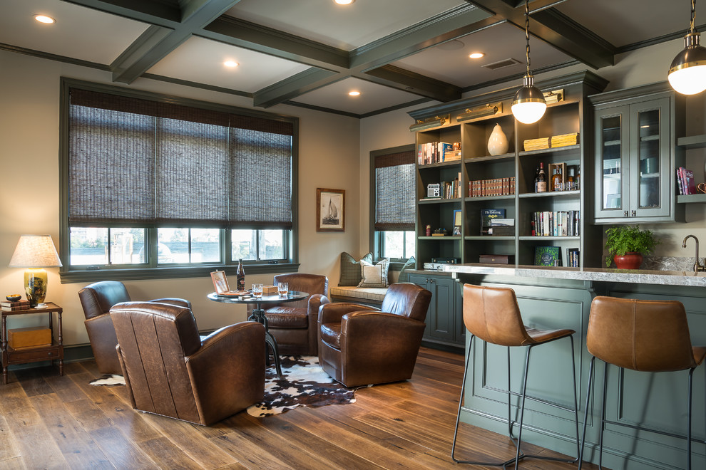 Aménagement d'un bar de salon avec évier classique avec un placard à porte affleurante, des portes de placards vertess, une crédence grise, un sol en bois brun et un sol marron.