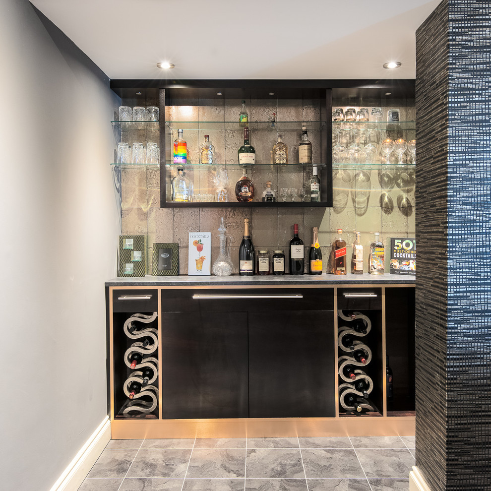Small modern l-shaped home bar in Berkshire with flat-panel cabinets, black cabinets, ceramic flooring and grey floors.