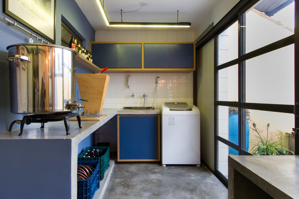 Idee per un bancone bar industriale di medie dimensioni con lavello da incasso, ante lisce, ante blu, top in cemento, paraspruzzi blu, pavimento in cemento, pavimento grigio e top grigio