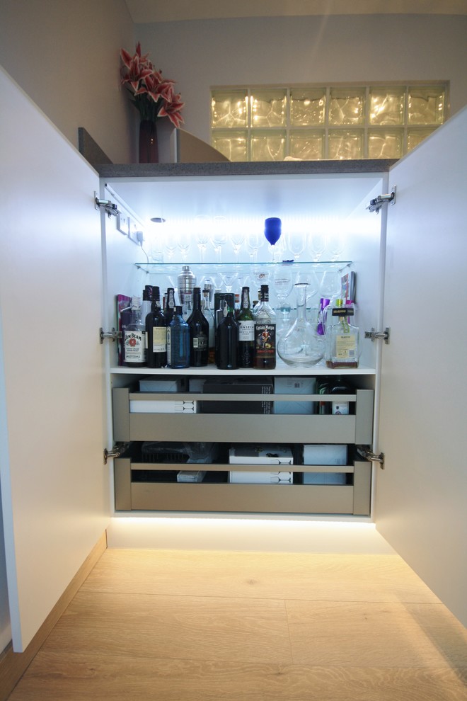 Inspiration for a large contemporary home bar in Essex with light hardwood flooring.