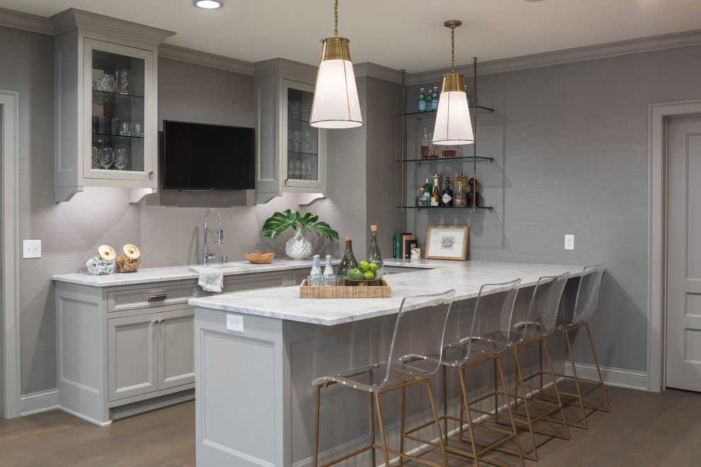 Photo of a medium sized classic l-shaped breakfast bar in Minneapolis with glass-front cabinets, white cabinets, marble worktops, brown floors, white worktops, a built-in sink and medium hardwood flooring.