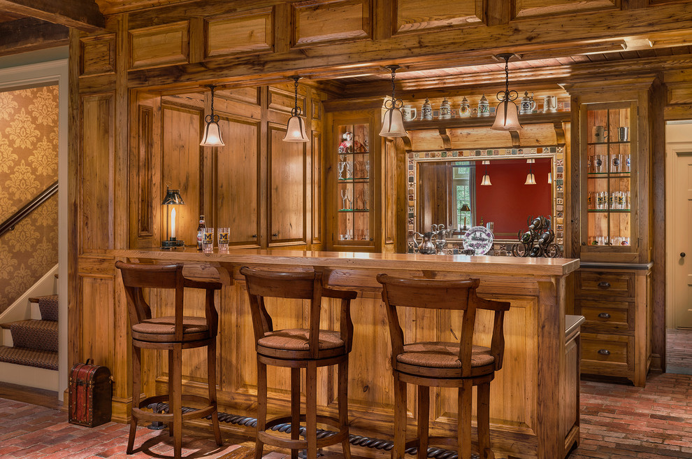 Diseño de bar en casa con barra de bar de galera tradicional con armarios estilo shaker, puertas de armario de madera oscura y suelo de ladrillo