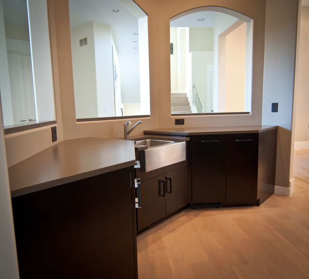Photo of a small contemporary galley dry bar in Grand Rapids with flat-panel cabinets, black cabinets, engineered stone countertops, light hardwood flooring, orange floors and grey worktops.