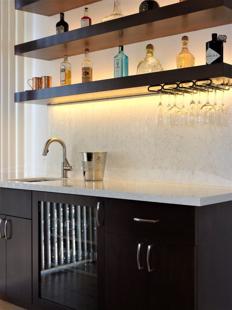Inspiration for a medium sized contemporary galley wet bar in San Francisco with a submerged sink, flat-panel cabinets, dark wood cabinets, engineered stone countertops, white splashback, stone slab splashback, light hardwood flooring and white worktops.