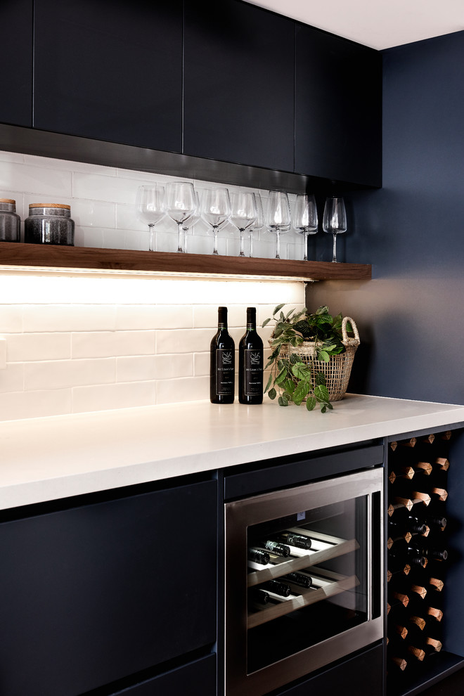 Inspiration for a mid-sized coastal single-wall home bar remodel in Sydney with flat-panel cabinets, quartz countertops, white backsplash, white countertops, subway tile backsplash and black cabinets