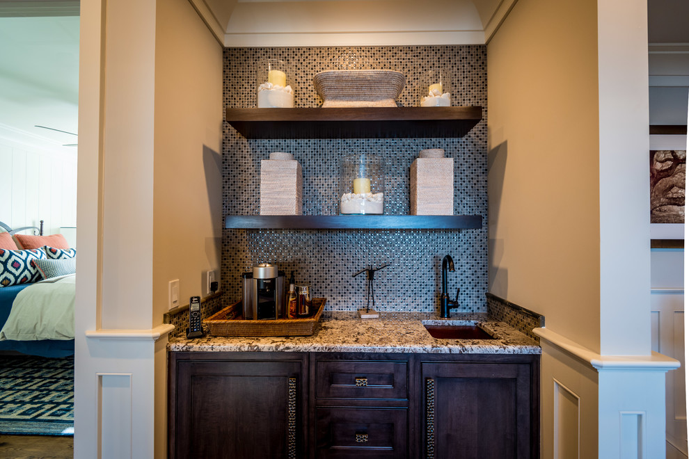 Inredning av en klassisk mellanstor parallell hemmabar med vask, med en undermonterad diskho, luckor med upphöjd panel, skåp i mörkt trä, granitbänkskiva, brunt stänkskydd och stänkskydd i mosaik