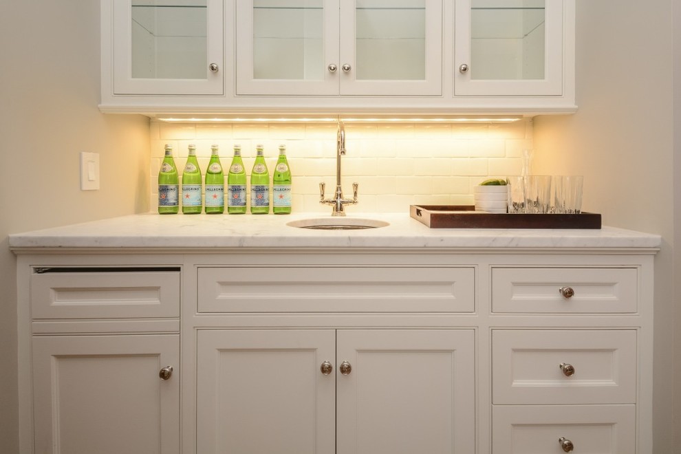 Design ideas for a small traditional single-wall wet bar in Boston with a submerged sink, recessed-panel cabinets, white cabinets, marble worktops, white splashback and metro tiled splashback.