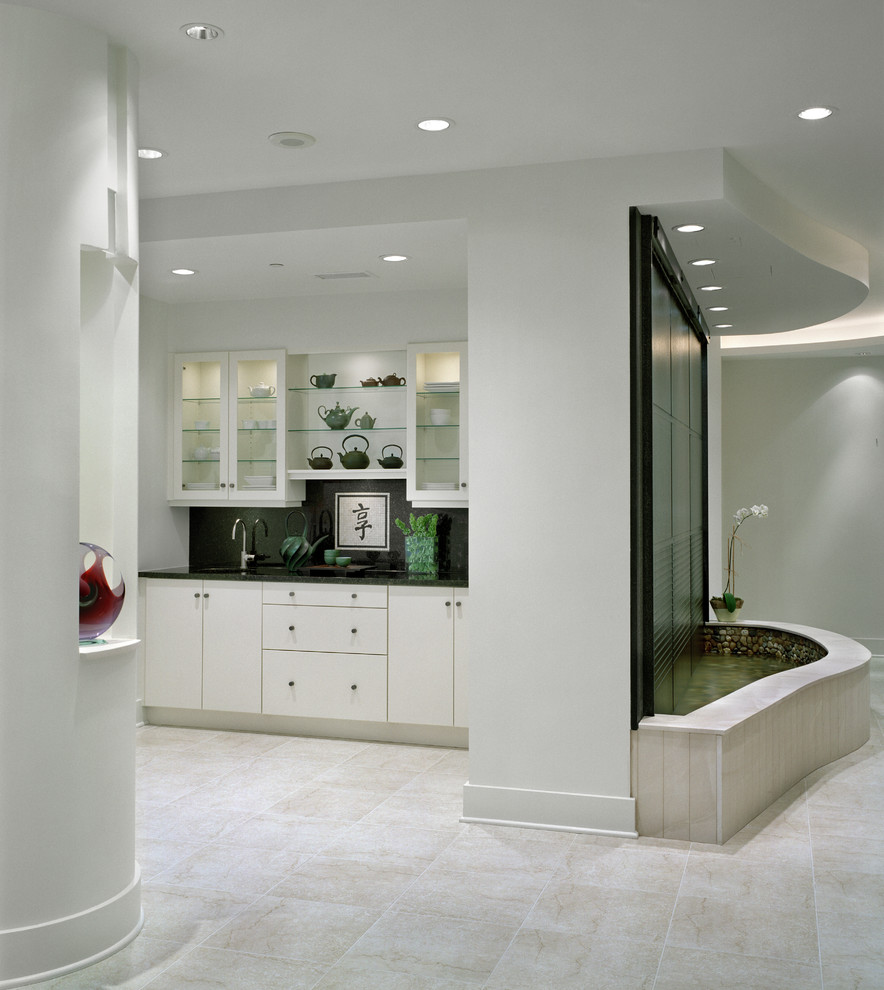 Idéer för en mellanstor modern linjär hemmabar med vask, med en undermonterad diskho, luckor med glaspanel, vita skåp, svart stänkskydd, travertin golv och beiget golv
