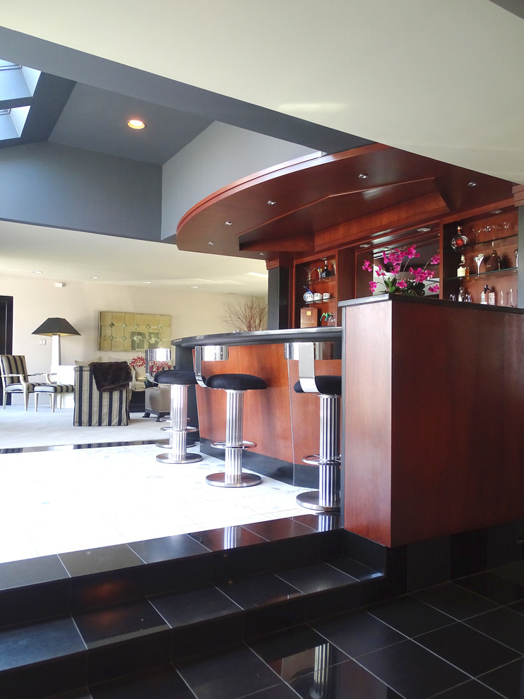 Exemple d'un bar de salon parallèle tendance en bois brun avec des tabourets, un évier encastré, un placard à porte plane et une crédence noire.
